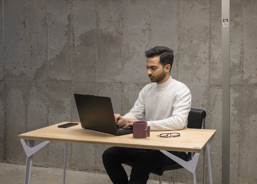 A man sitting at a desk using a laptop to explore the top automated proposal software.